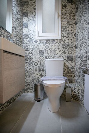 A bathroom with patterned tiles, a toilet, a sink, and a cabinet. - Luxurious 4 Bdrm 3Bath Apt 1- Athens (Athens)