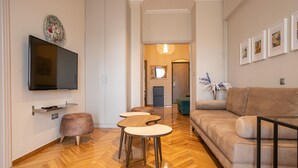 Een moderne woonkamer met een flatscreen televisie, een bank, twee ronde tafels en een salontafel.