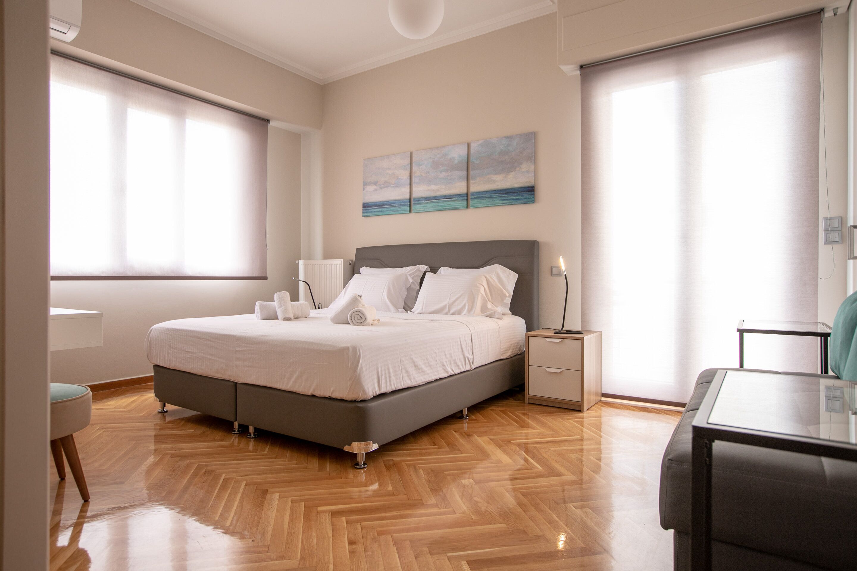 A modern bedroom with a large bed, bedside tables, a desk, and a chair.