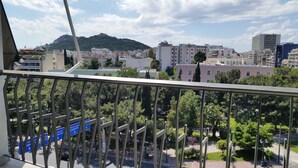 Een balkon met uitzicht op een stadsgezicht, inclusief gebouwen en een heuvel in de verte.