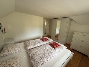 Un dormitorio con cama, dos almohadas, cómoda y armario.