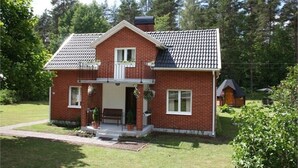 Een huis van baksteen met twee verdiepingen, een pannendak, een voortuin en een kleine aangebouwde garage.