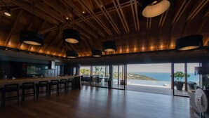 A spacious kitchen with a bar area, large windows, and a view of the sea. - Villa Jade – Zen-Inspired Oceanview Estate with Spa, Cinema & Infinity Pool in St. Barths (Gustavia)
