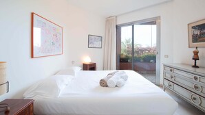 A hotel room with a bed, a nightstand, a dresser, and a large window with a view.