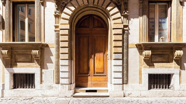 A historic building with a large wooden door, arched entrance, and classical architectural details. - Colosseum Terrace Apartment (Roma)