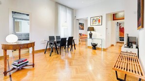 A modern living room with a dining area, a wooden coffee table, and a TV stand. - Colosseum Terrace Apartment (Roma)