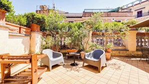 A patio with two chairs, a small table, and a wooden drying rack. - Colosseum Terrace Apartment (Roma)