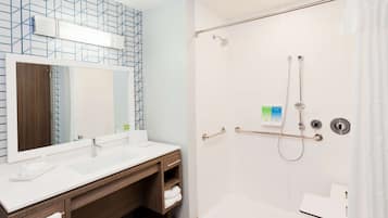 A modern bathroom with a large mirror, two sinks, a shower with a glass door, and a towel rack.