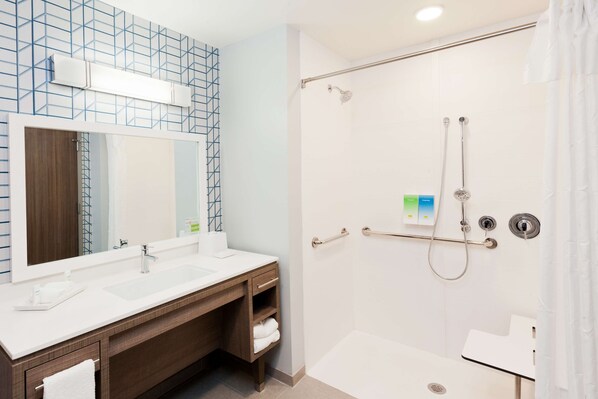 Um banheiro moderno com um espelho grande, duas pias, chuveiro com porta de vidro e porta-toalhas.