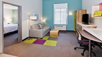 A hotel room with a bed, a sofa, a desk, and a television.