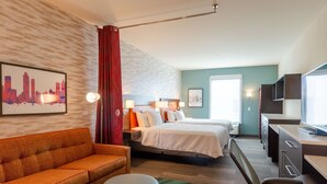 Una habitación de hotel con cama, escritorio, silla, sofá y televisor.