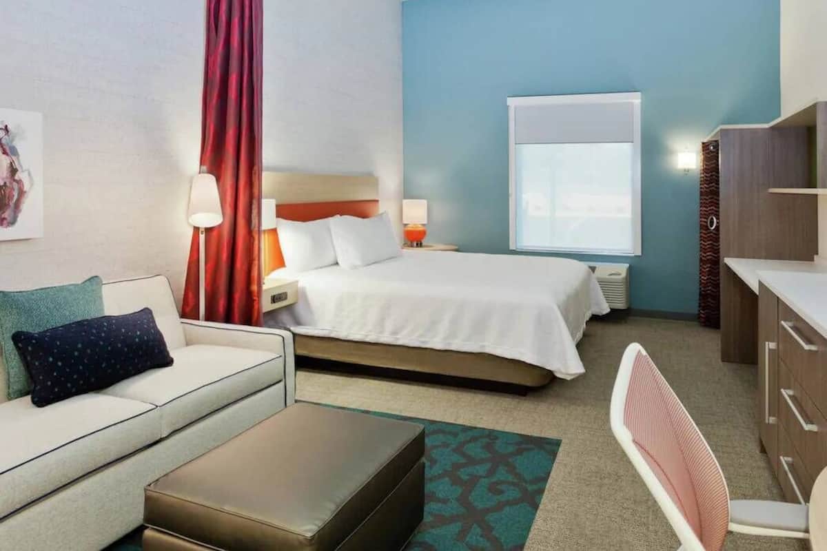Una habitación de hotel con una cama, un sofá, un escritorio y una silla.