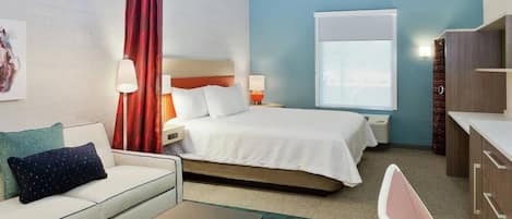 A hotel room with a bed, a sofa, a desk, and a chair.
