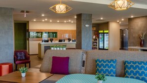 Un vestíbulo moderno de hotel con mostrador de recepción, zona de estar y máquinas expendedoras.