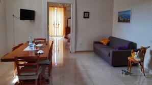 Un comedor con una mesa y sillas de madera, un sof á y un televisor montado en la pared.