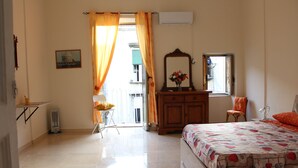 Un dormitorio con cama, cómoda, silla, espejo y ventana con cortinas.