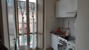 Cocina compacta con lavadora, lavamanos y ventana con cortinas.
