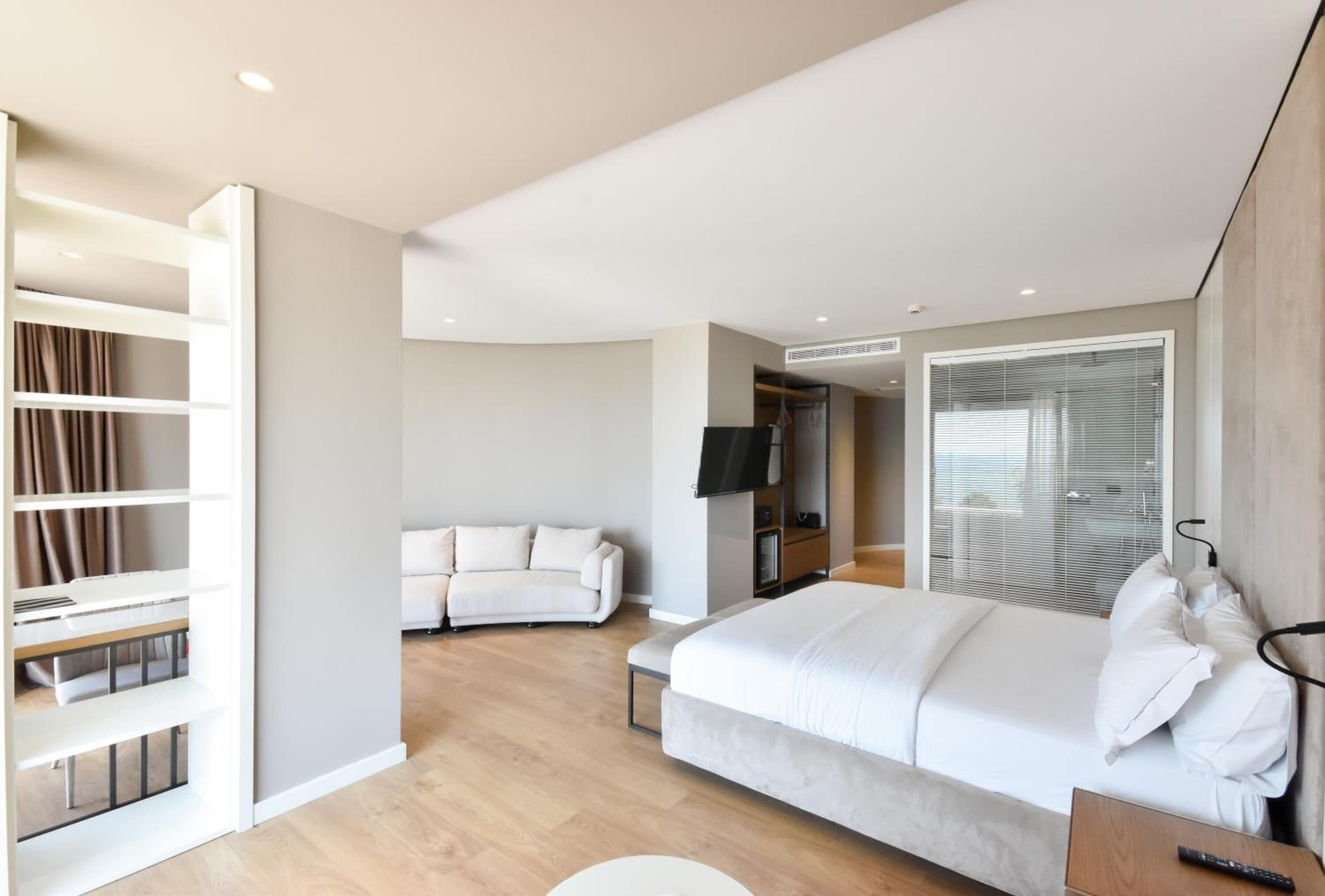 Un dormitorio moderno con una cama grande, televisión integrada y vestidor.