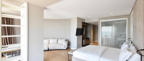 Un dormitorio moderno con una cama grande, televisión integrada y vestidor.