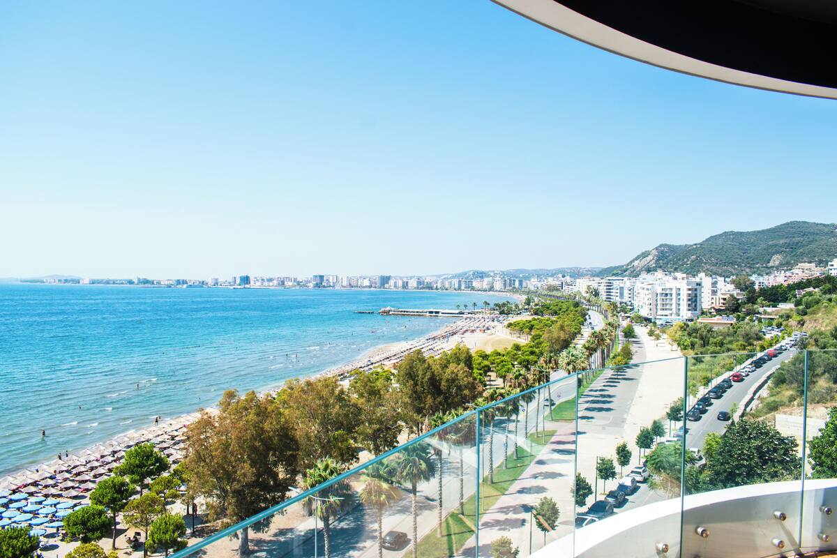 A coastal cityscape with a beach, promenade, and clear blue sky.
