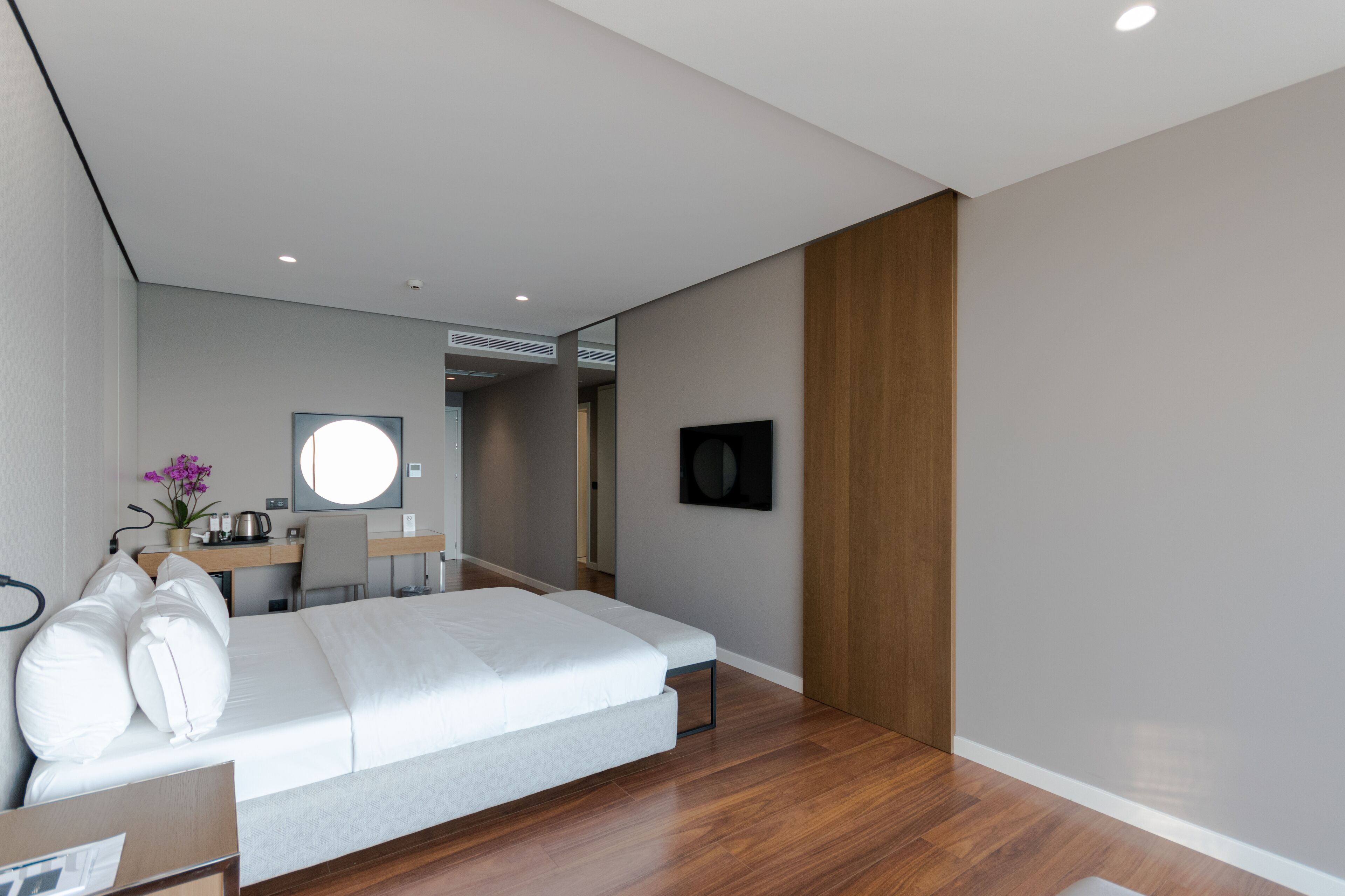 A modern hotel room with a large bed, a desk, and a mirror.