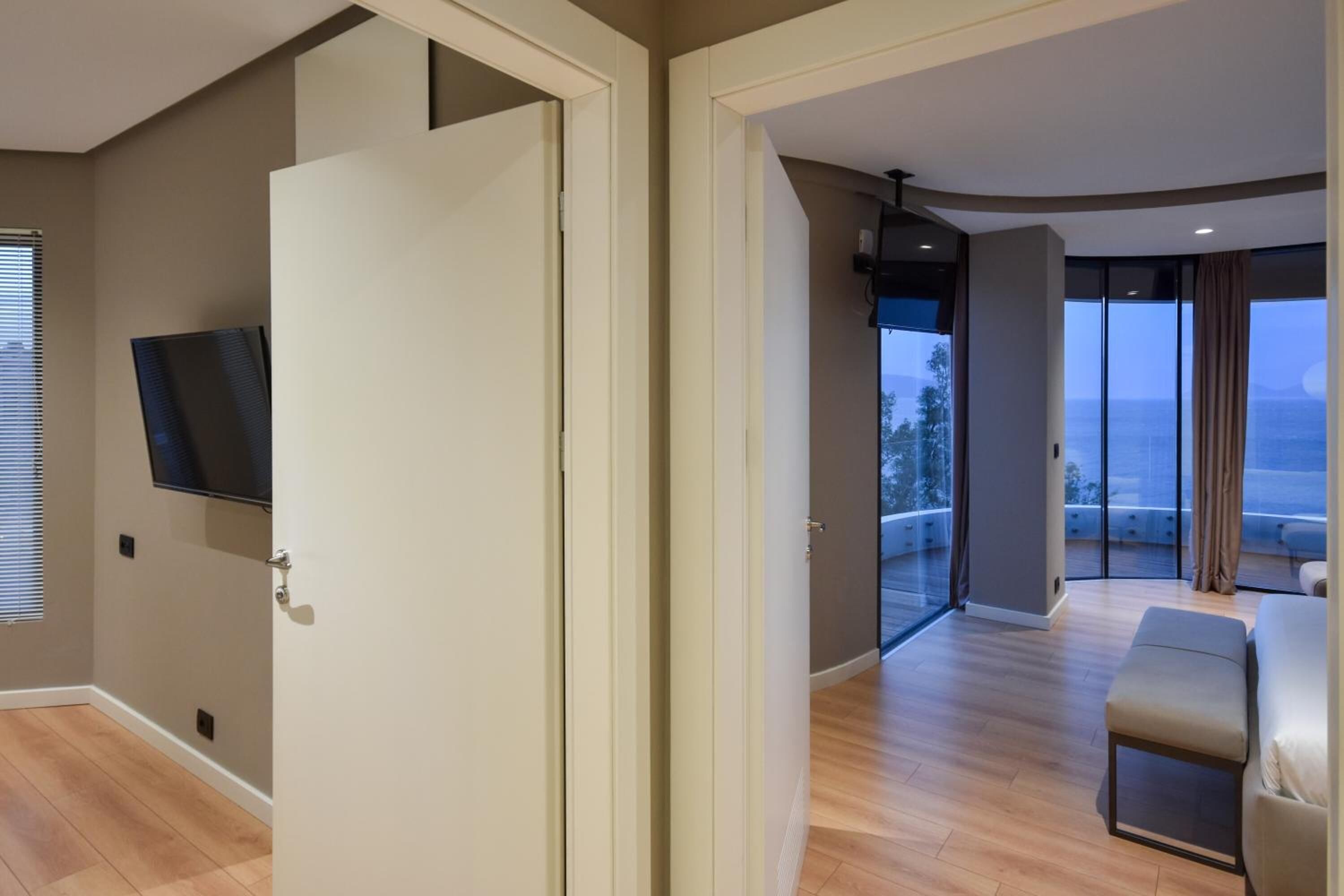 A modern hotel room with a large sliding glass door leading to a balcony with a view of the sea.