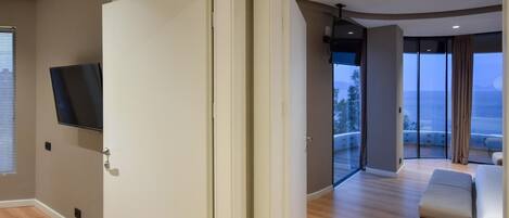 A modern hotel room with a large sliding glass door leading to a balcony with a view of the sea.