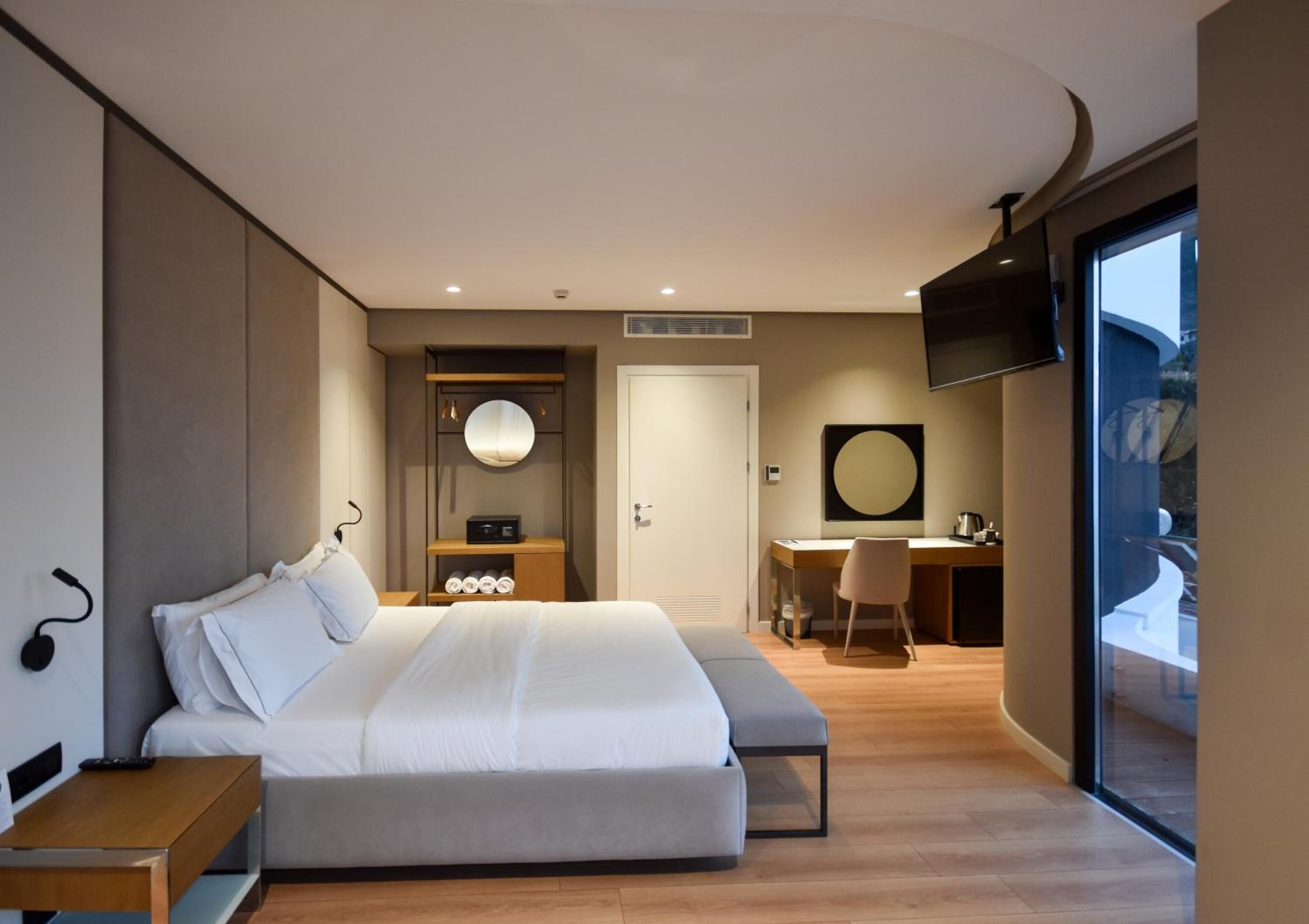 Un dormitorio moderno con una cama grande, un escritorio y una televisión.