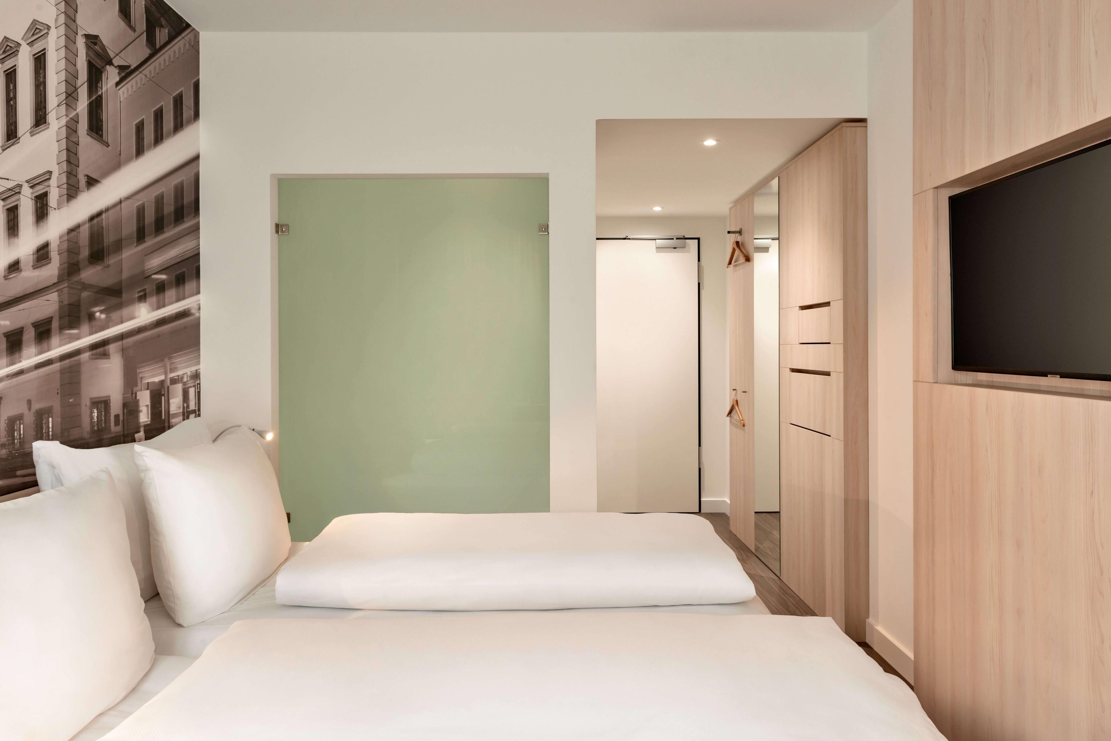 A hotel room with a bed, a wardrobe, a television, and a door leading to another room.