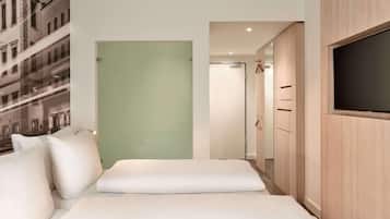 A hotel room with a bed, a wardrobe, a television, and a door leading to another room.
