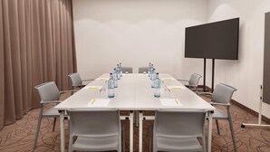 A conference room with a long table, chairs, a projector screen, and water bottles. - Super 8 by Wyndham Augsburg (Augsburg)