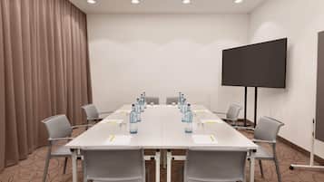 A conference room with a long table, chairs, a projector screen, and water bottles.