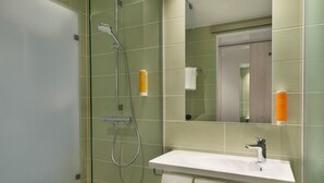 A bathroom with a glass shower enclosure, a white sink, and a mirror above it. - Super 8 by Wyndham Augsburg (Augsburg)