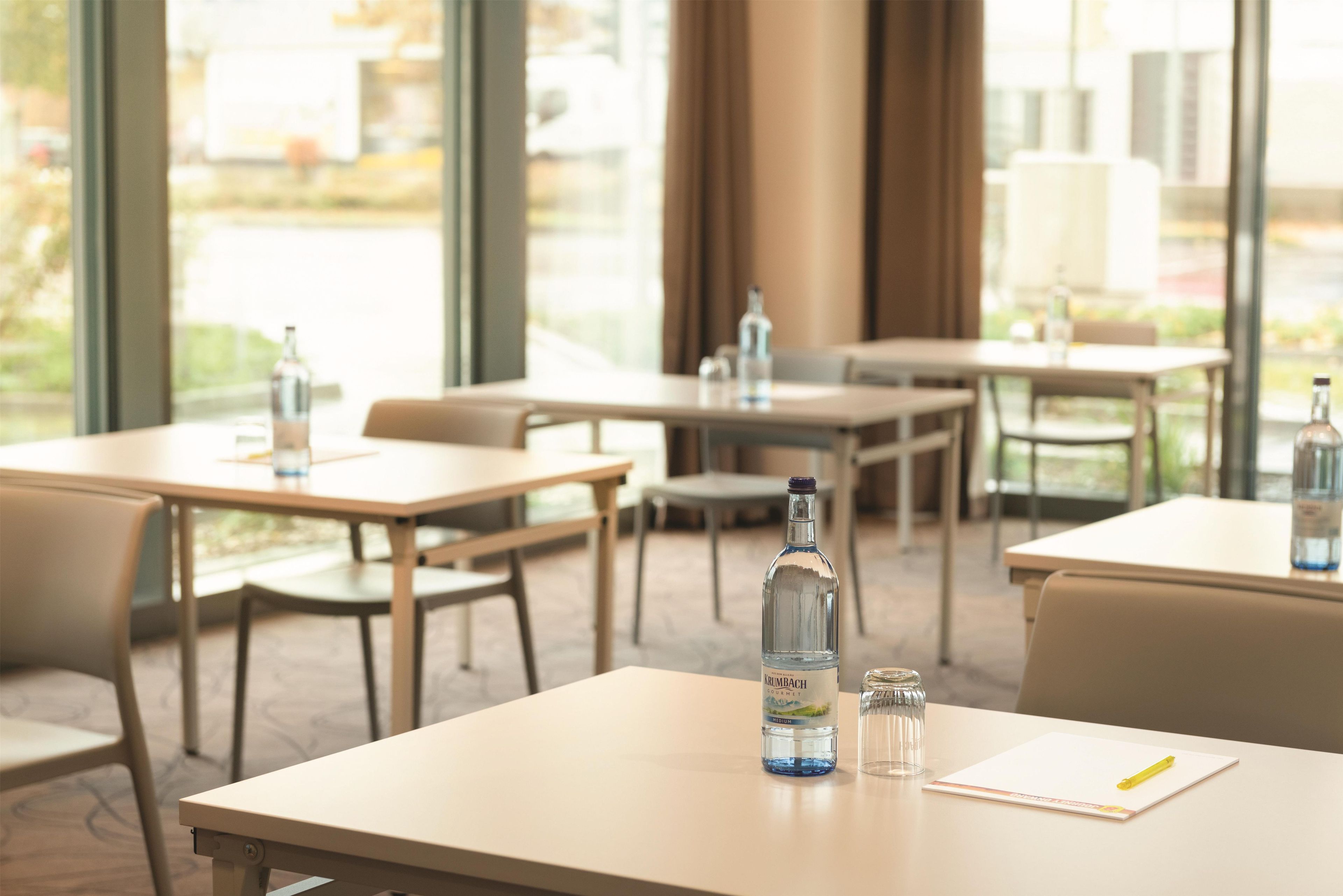 A hotel dining area with tables, chairs, and bottles of water.