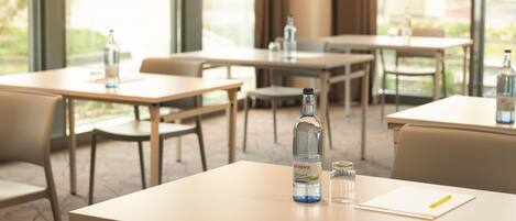A hotel dining area with tables, chairs, and bottles of water.