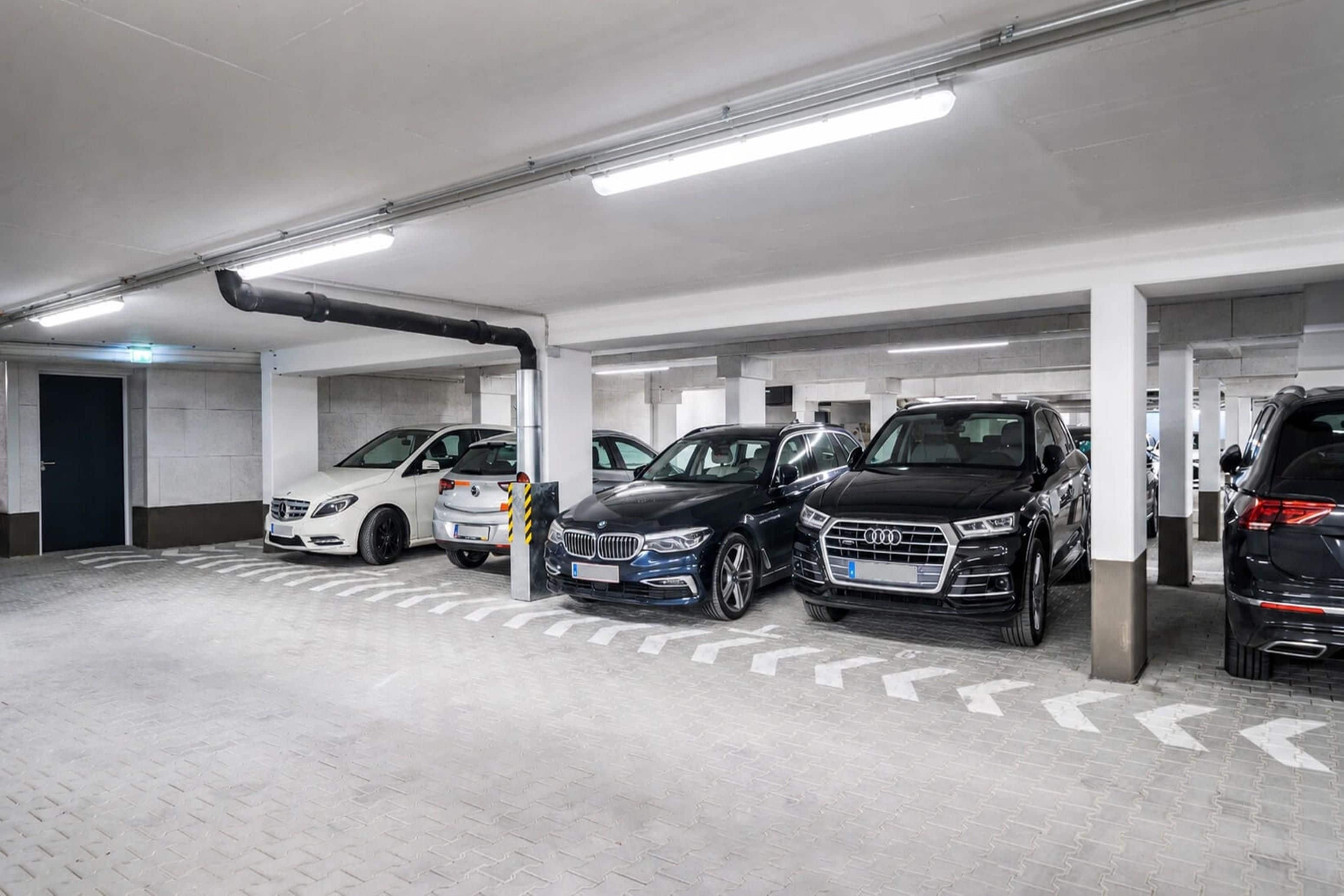 Un estacionamiento subterráneo de varios niveles con automóviles estacionados en espacios designados.