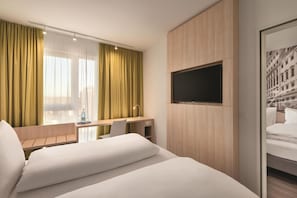 A hotel room with a bed, a desk, a chair, a TV mounted on the wall, and a window with curtains. - Super 8 by Wyndham Augsburg (Augsburg)