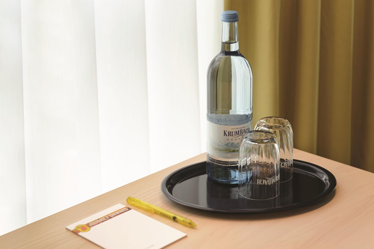Eine Flasche Krumbach Wein, zwei Gläser, ein Stift und ein Notizblock auf einem Tablett.