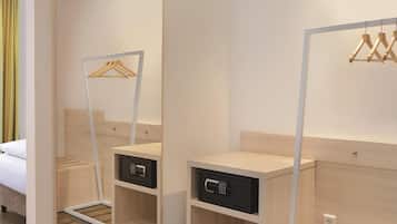Ein Hotelzimmer mit Bett, Spiegel, Kleiderschrank und Nachttisch mit Bedienfeld.
