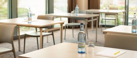Een restaurantruimte in een hotel met tafels, stoelen en waterflessen.