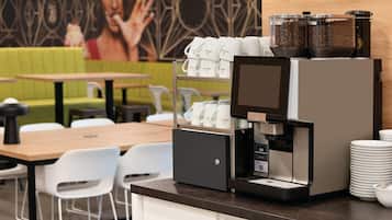 Una cafetera con pantalla digital, un molinillo de café y una jarra para servir café.