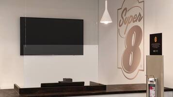 Una recepción con un televisor de pantalla plana montado encima, un cartel en la pared con el número '8', y un extintor a la derecha.