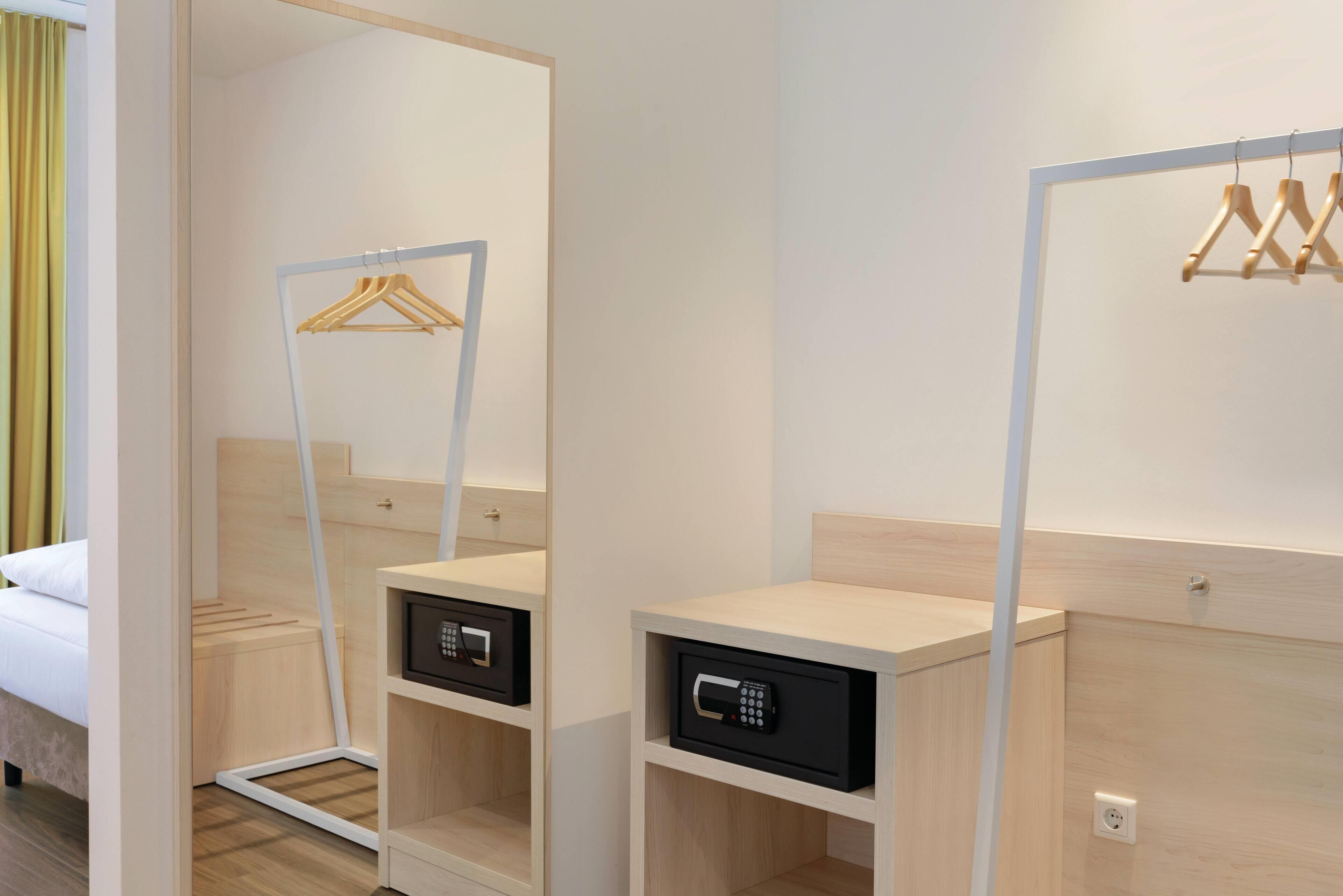 Ein Hotelzimmer mit einem Bett, einem Spiegel, einem Kleiderschrank und einem Safe.