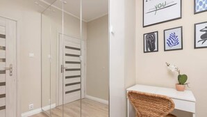 A modern room with a mirrored closet, a white desk, and framed artwork on the wall.