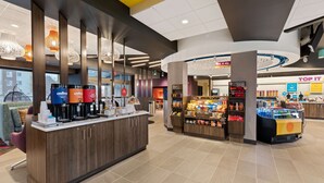 Een moderne hotel lobby met een koffiehoek, een snackbar en een 'Top It' winkel.