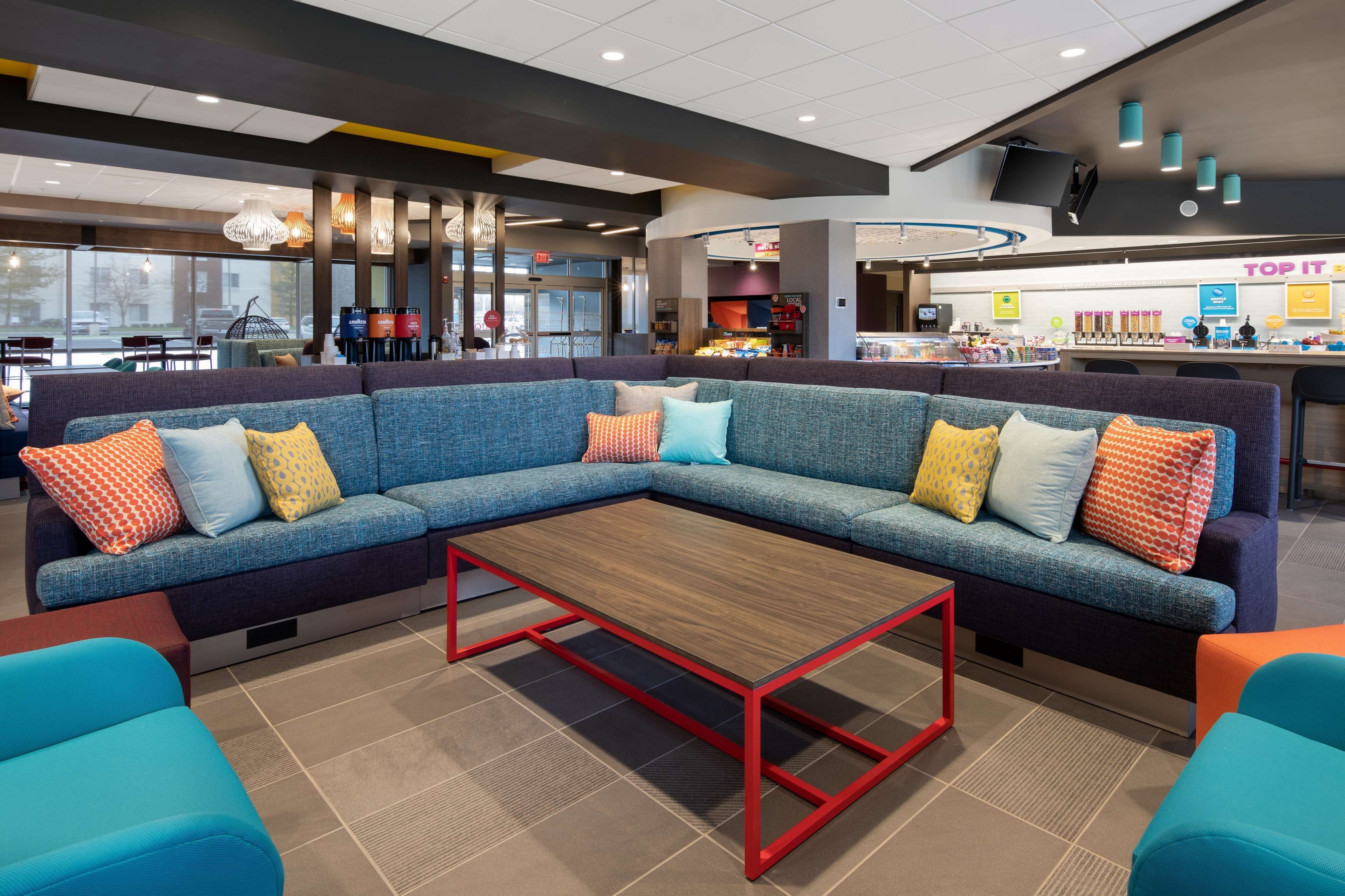 A modern lounge area with a sectional sofa, a wooden coffee table, and colorful chairs.