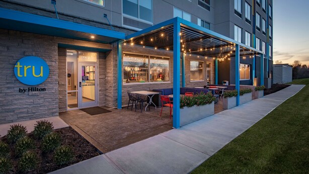Een modern hotel met een overdekt terras, een stenen gevel en een kleurenschema in blauw en grijs.