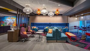 Een moderne lobby met een receptiebalie, zitgedeeltes en een muurschildering van bezienswaardigheden in Cincinnati.