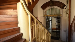 Uma escada de madeira com corrimão de metal que leva a uma porta com uma placa em cima.