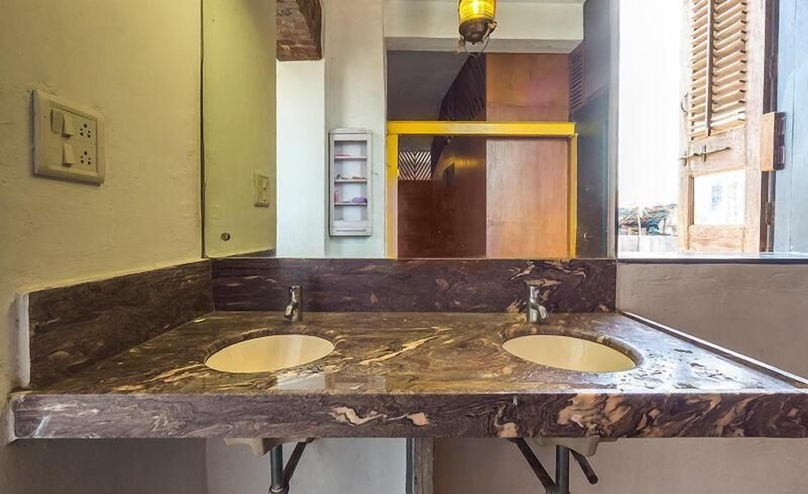 A bathroom with two sinks, a mirror, and a yellow light fixture.